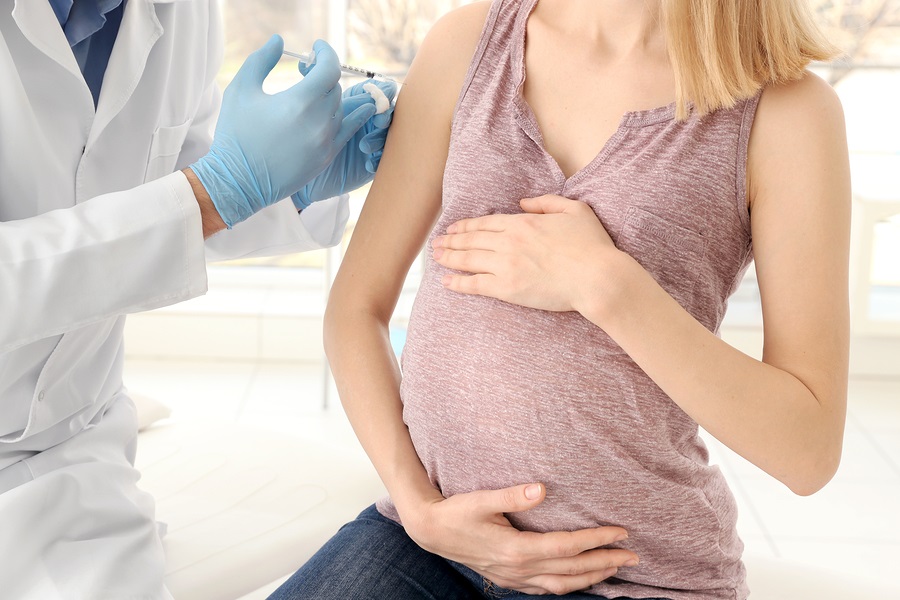Male doctor vaccinating young pregnant woman