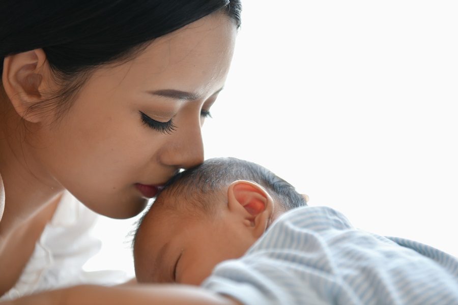 Newborn Concept. Mother and child on a white bed.